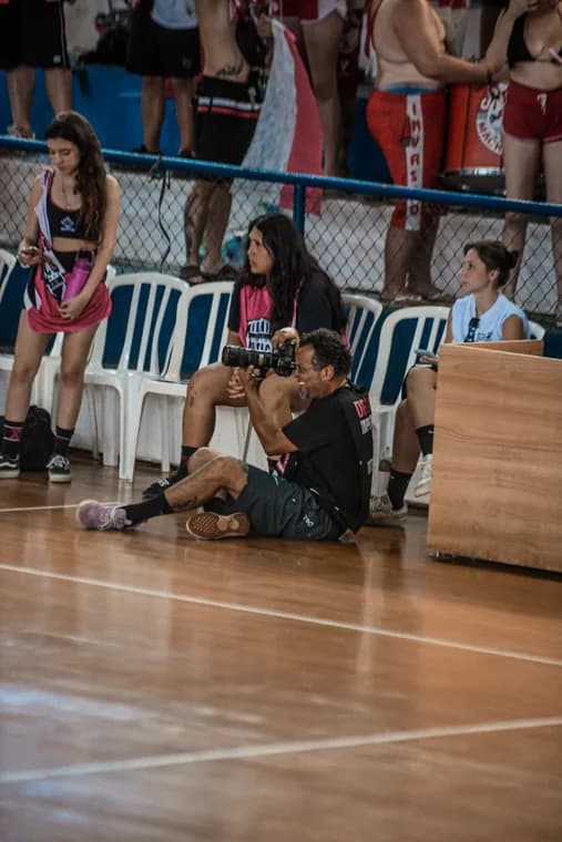 Fotógrafo sentado à beira da quadra durante a competição