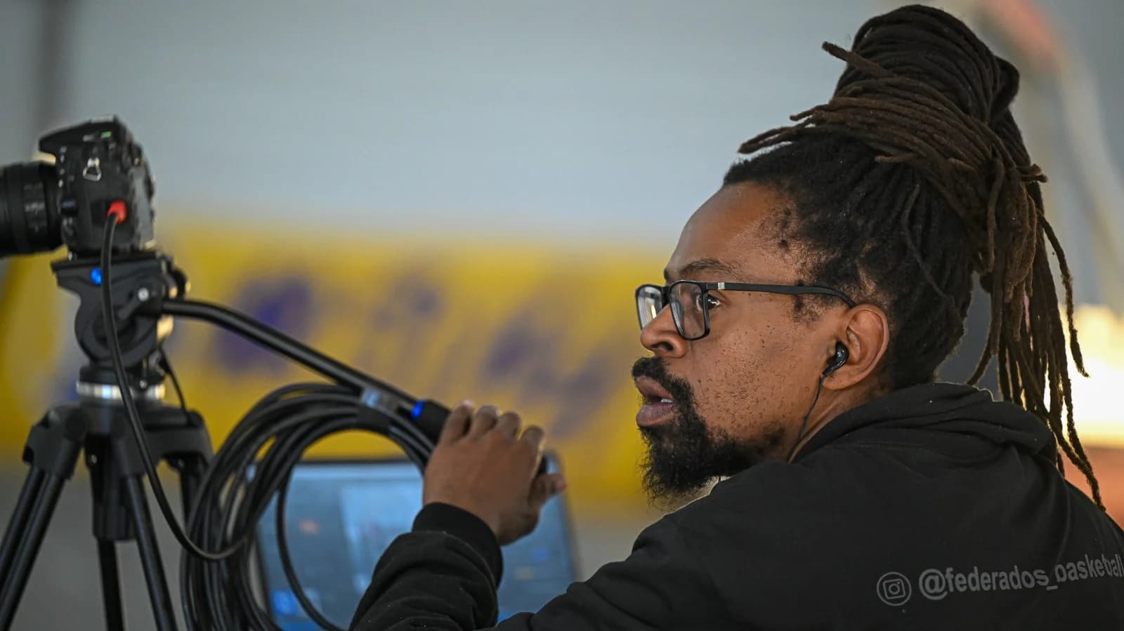 Operador da Federados com headset, câmera e equipamentos de transmissão à beira da quadra